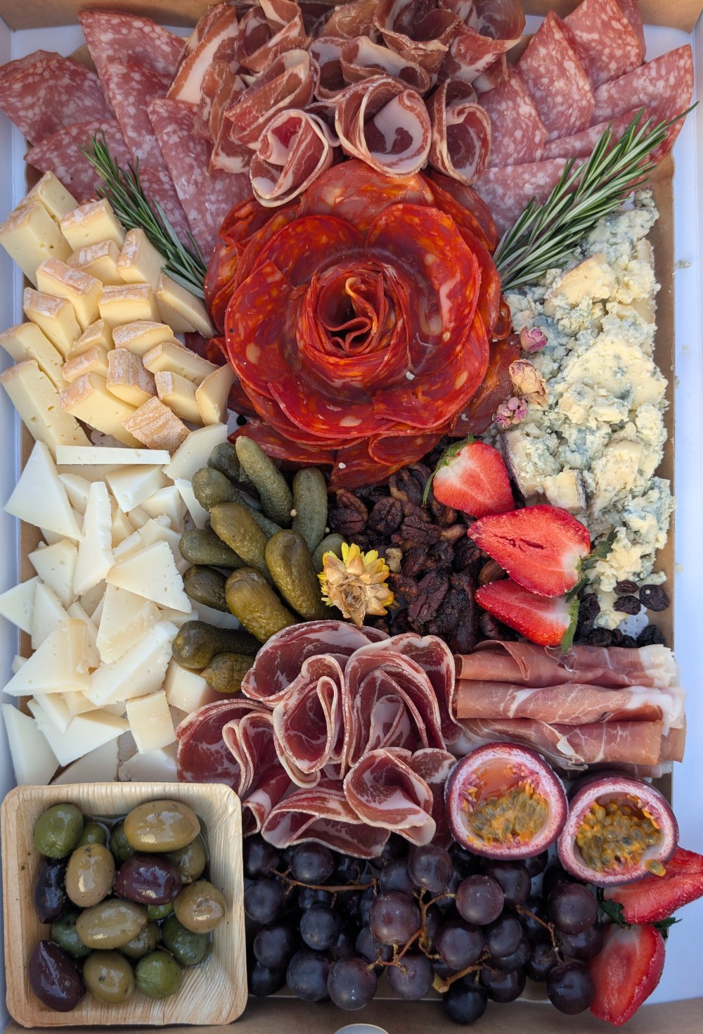 A charcuterie box from the Meltdown kitchen: a chorizo rose, cured meats, cheeses, olives, grapes and strawberries