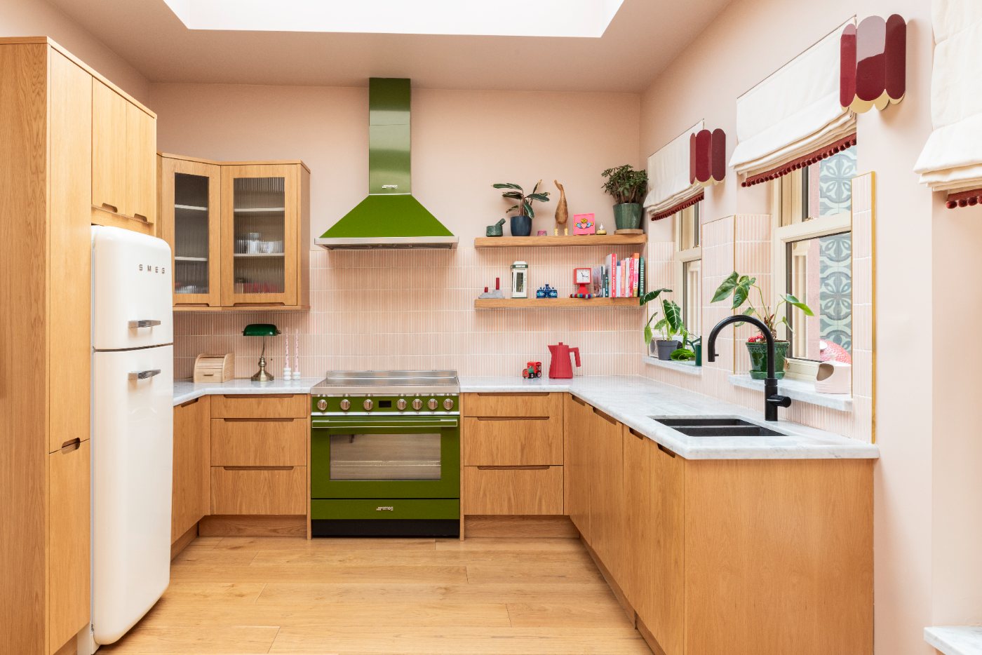 Kitchen with oak cabinets, pink tiles and a green Smeg range