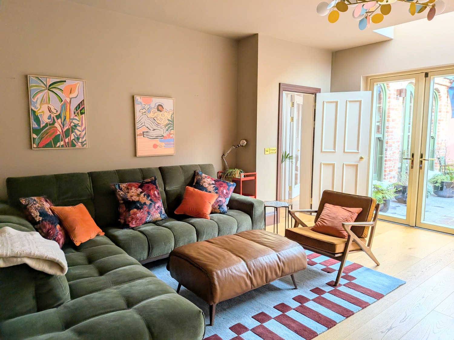 Living room with a green corduroy sofa and doors out to the courtyard