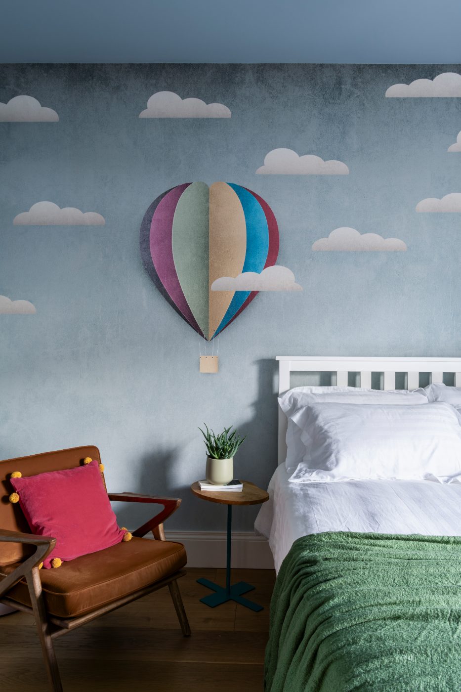 Twin room with cloud wallpaper and a green throw