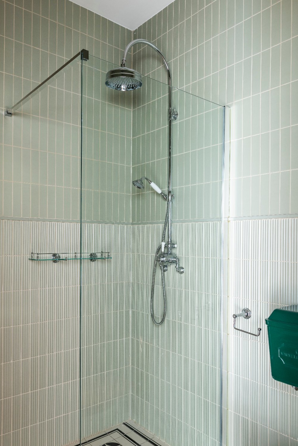 Walk-in shower with sage green tiles and a chrome rainfall shower