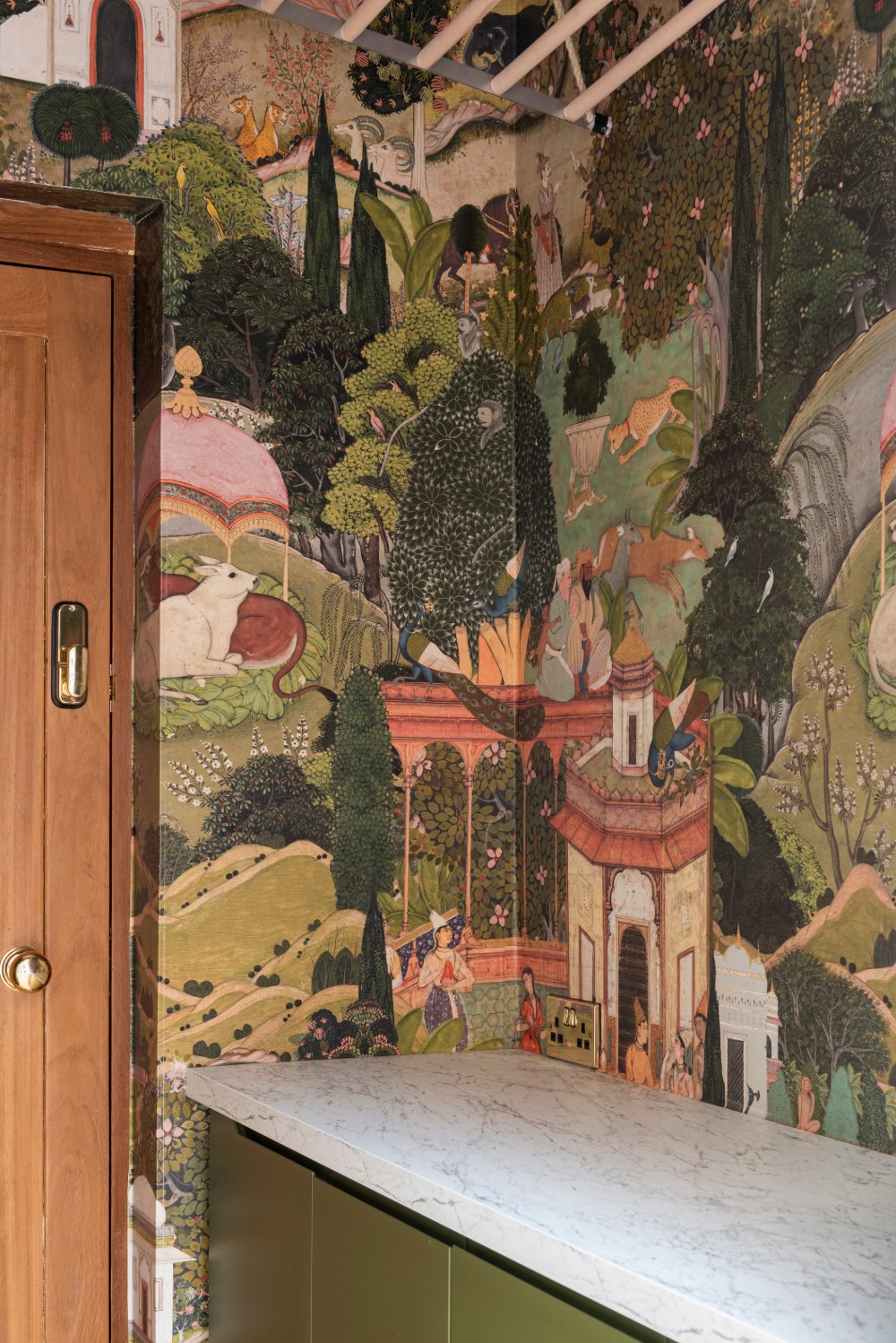 Utility room with painted garden wallpaper above olive cabinets